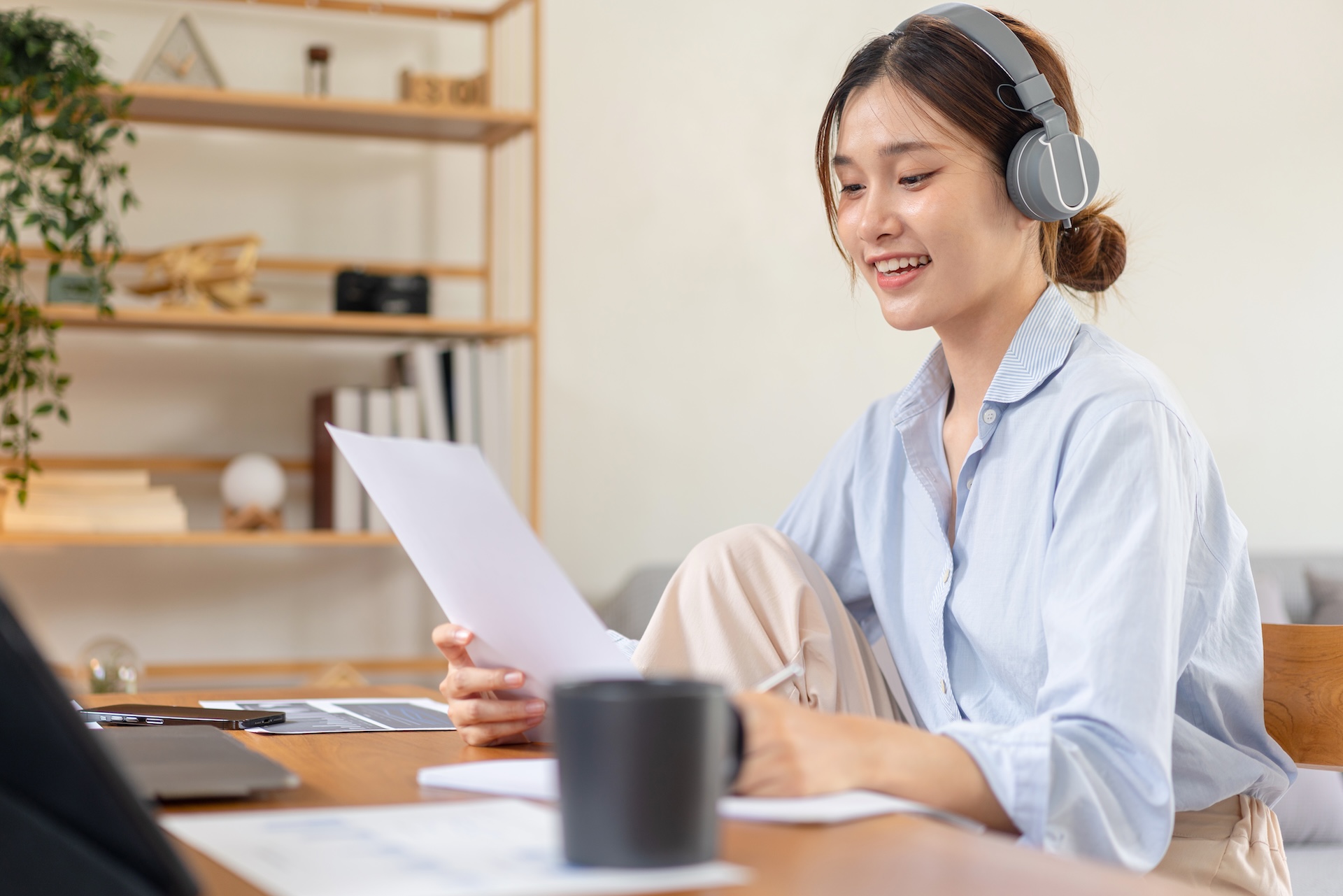 Female freelance is reading business data on laptop and document to writing information on notebook